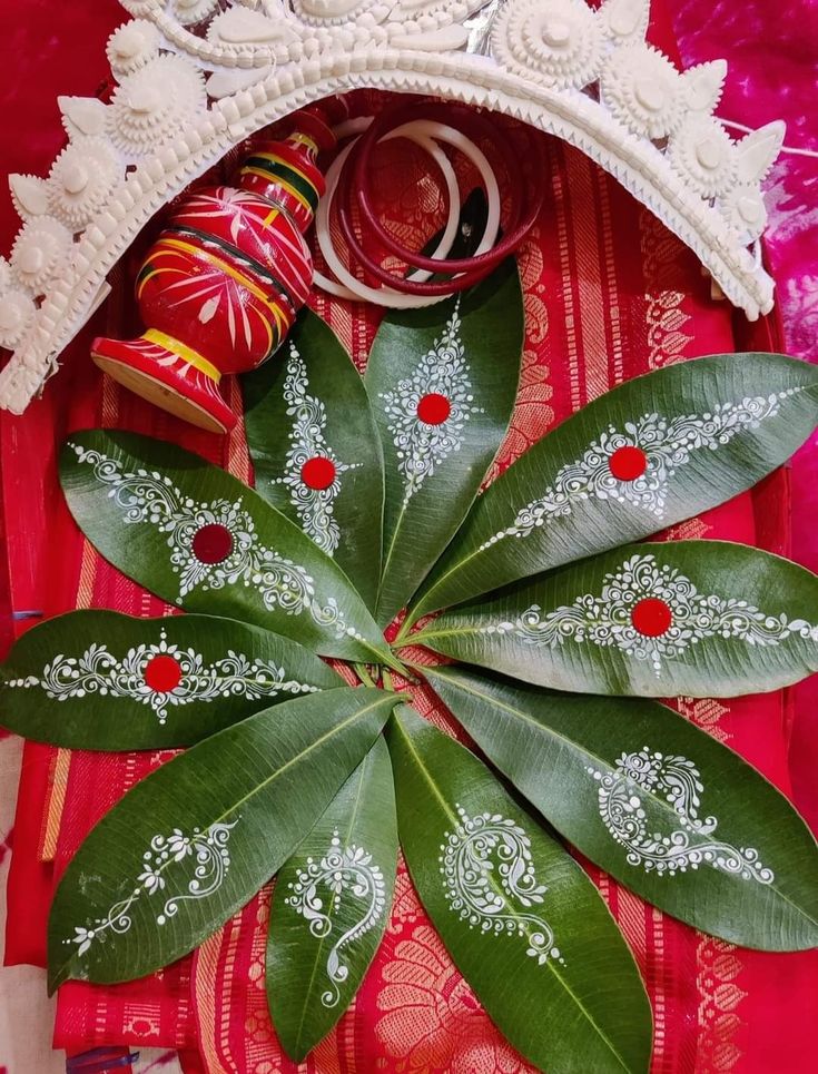 a green plant with red and white designs on it's leaves is surrounded by other decorative items