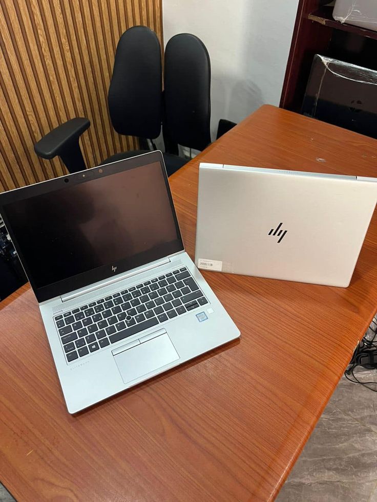 an open laptop computer sitting on top of a wooden table next to a white box