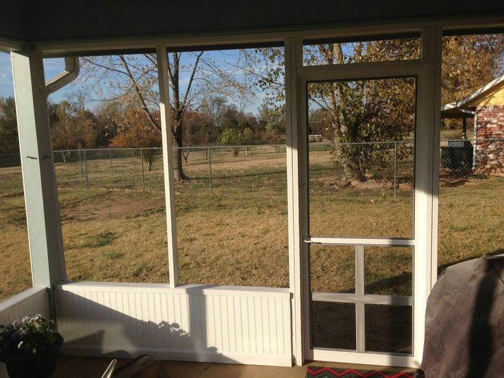 an open screen door on the outside of a house with grass and trees in the background