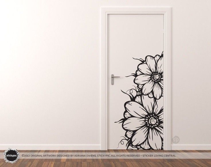 an open door with black and white flowers painted on the wall next to hardwood flooring