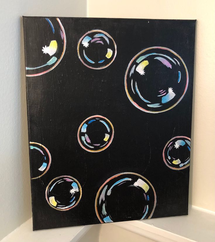 a black painting with multicolored bubbles hanging on the wall next to a toilet