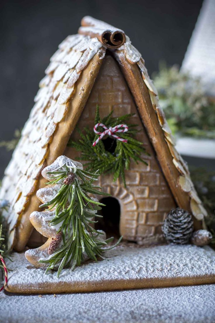 a gingerbread house decorated with pine cones and cinnamon sticks