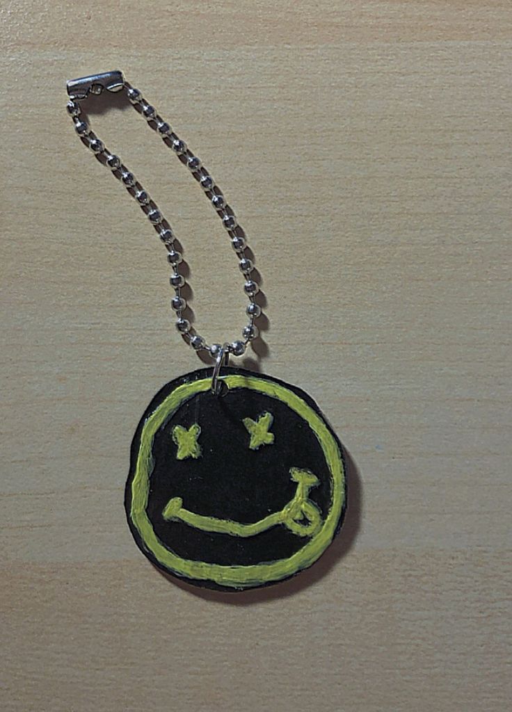 a black and yellow smiley face on a chain