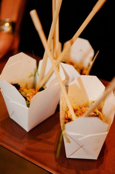 three white boxes filled with food on top of a wooden table next to chopsticks