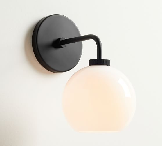 a light that is on the wall next to a white wall mounted lamp with a black arm