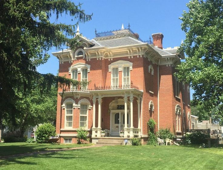 an old red brick house sitting on top of a lush green field