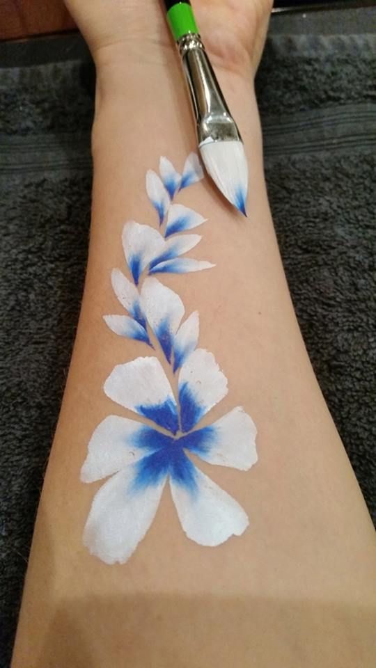 a person's arm with blue and white flowers painted on the side of it