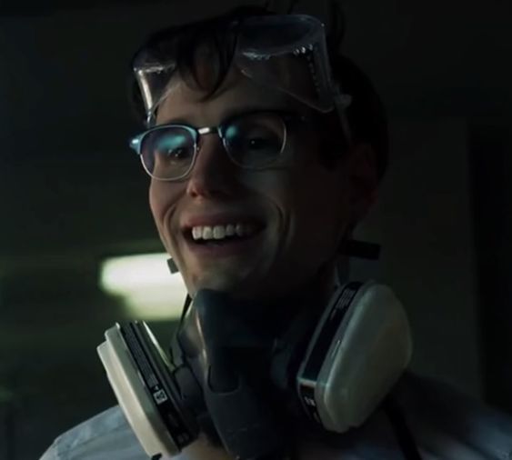 a man wearing headphones and glasses smiling at the camera