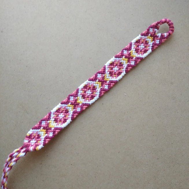 a pink and yellow beaded wristband on a table with a white cord in the middle