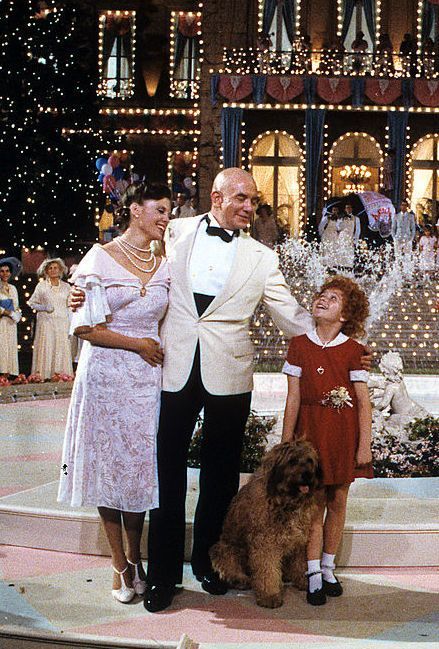 a family posing for a photo in front of a christmas tree with lights on it