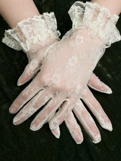 a pair of white gloves with lace on them