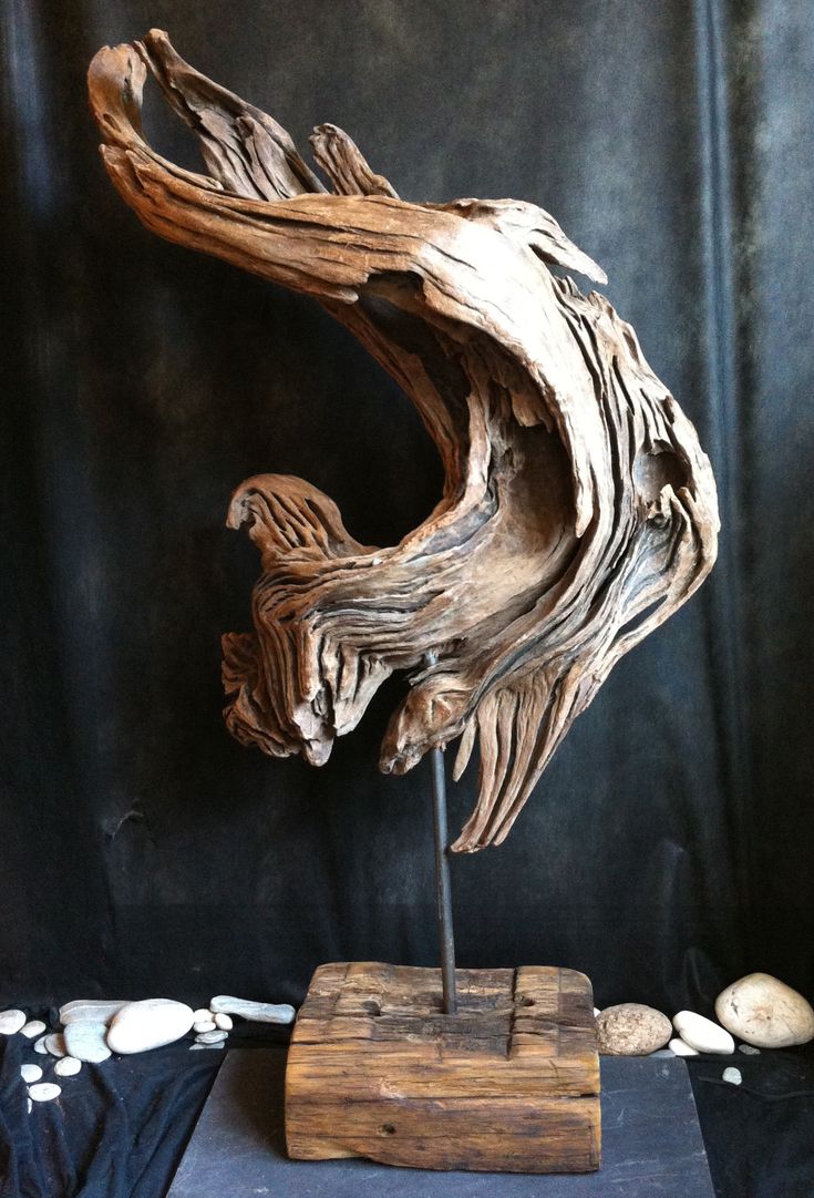 a piece of driftwood is displayed on a wooden stand in front of a black background