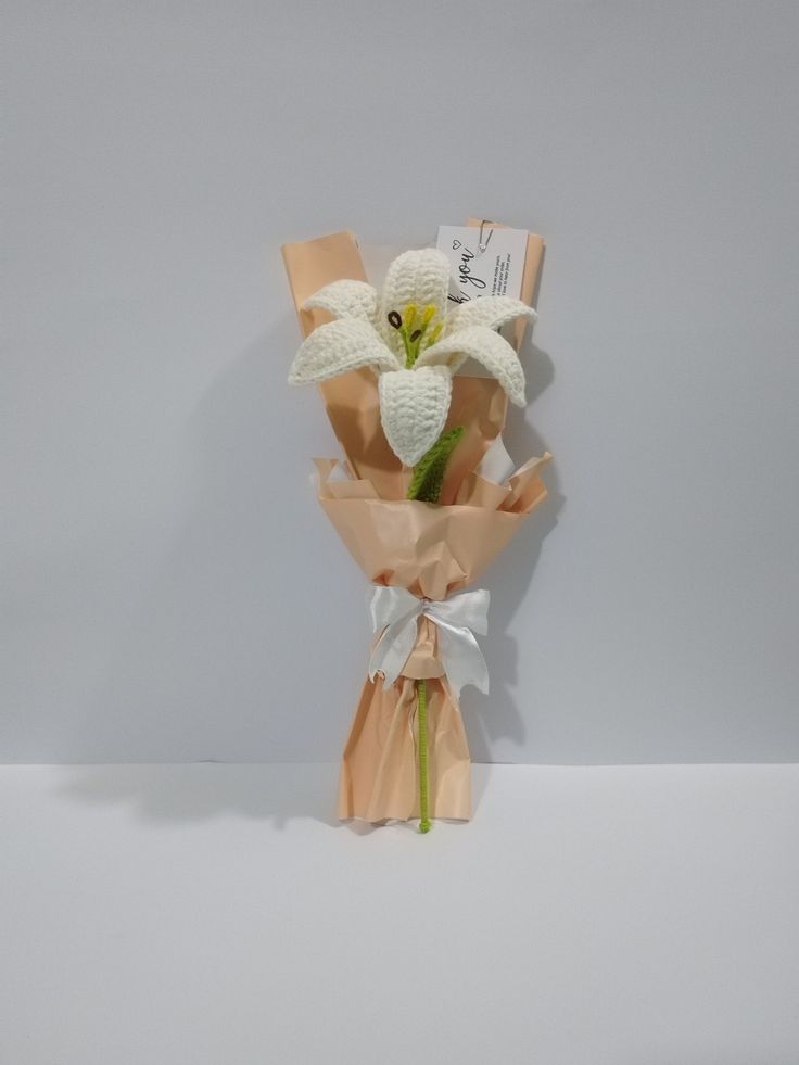 a bouquet of flowers is wrapped in brown paper and tied with a white ribbon on the end