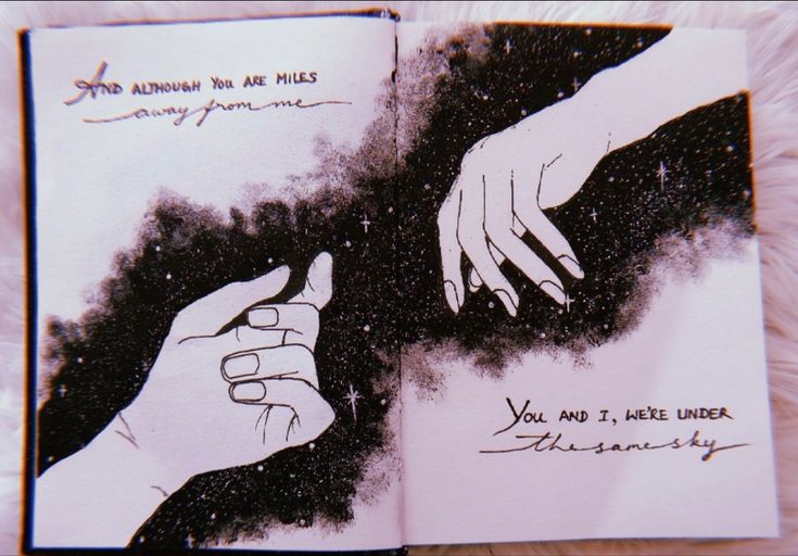 an open book with two hands reaching for each other's hand and writing on it