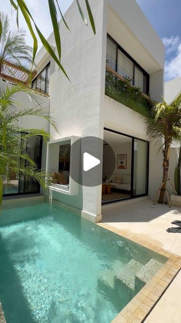 a house with a swimming pool in front of it and palm trees around the pool