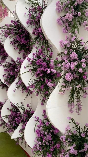 purple flowers are growing on the side of white vases that have been stacked together