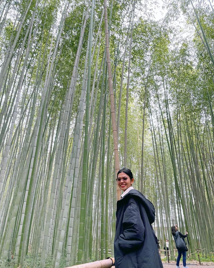 a woman standing in front of tall bamboo trees