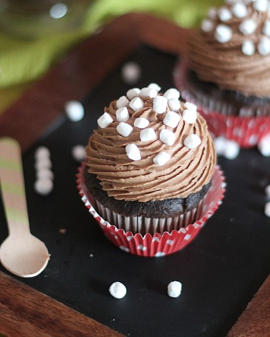 three cupcakes with chocolate frosting and marshmallows on a tray