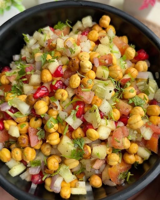 a black bowl filled with corn and vegetables