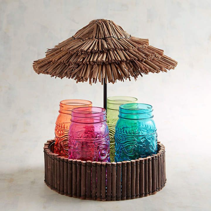 three mason jars sitting on top of a bamboo holder with an umbrella over it and the lids are painted multicolored