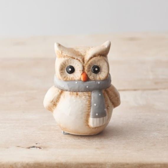 an owl figurine with a scarf around it's neck on a wooden surface