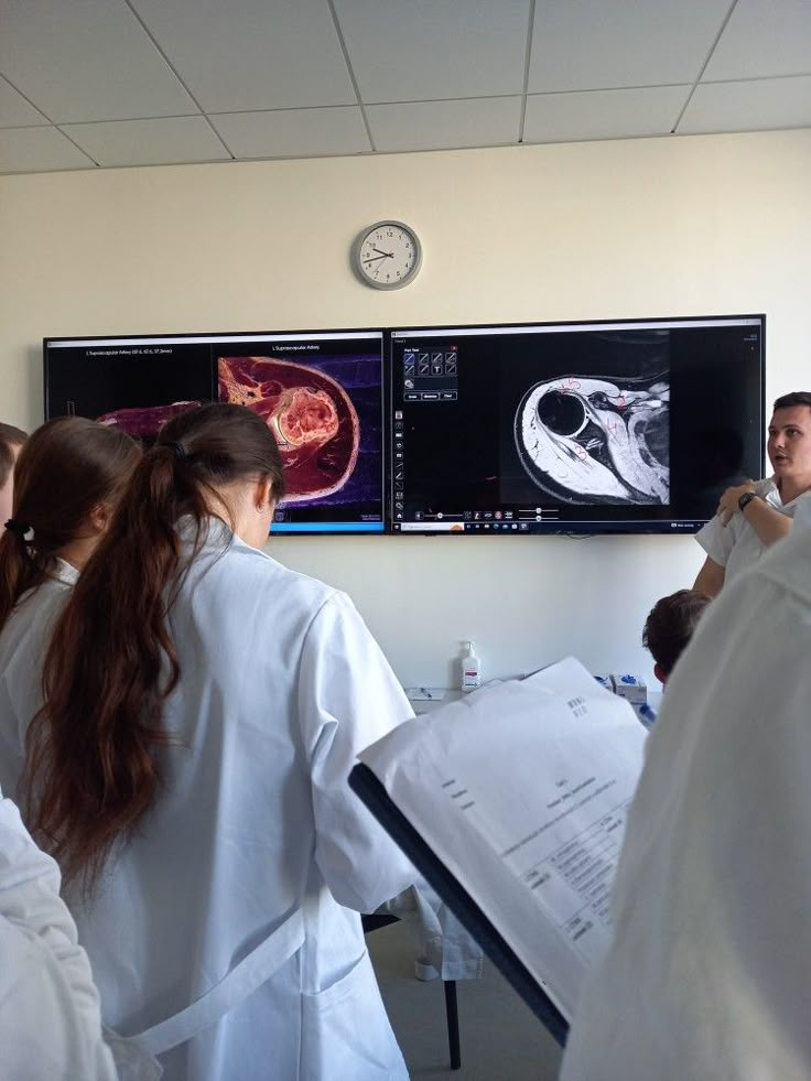 some people in white lab coats are looking at mri images on the wall behind them