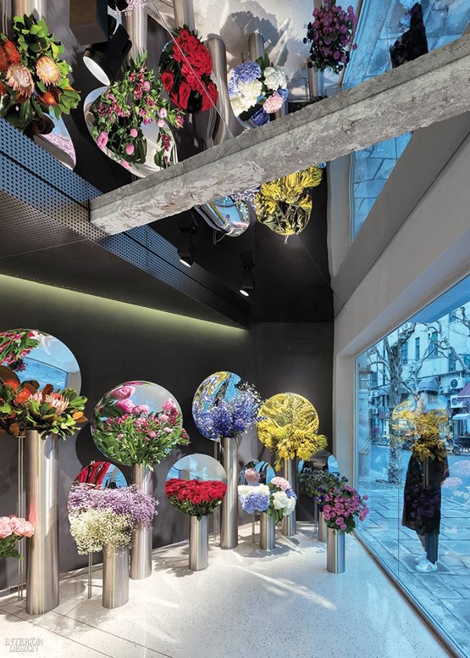 a bunch of vases filled with flowers on top of a white floor next to a window