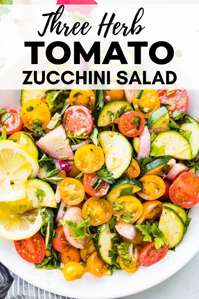 a white bowl filled with cucumber, tomatoes and other vegetables on top of a table