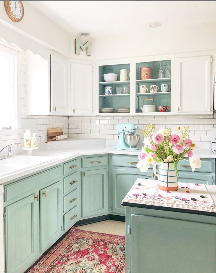 a kitchen filled with lots of green cabinets and white counter tops next to a rug