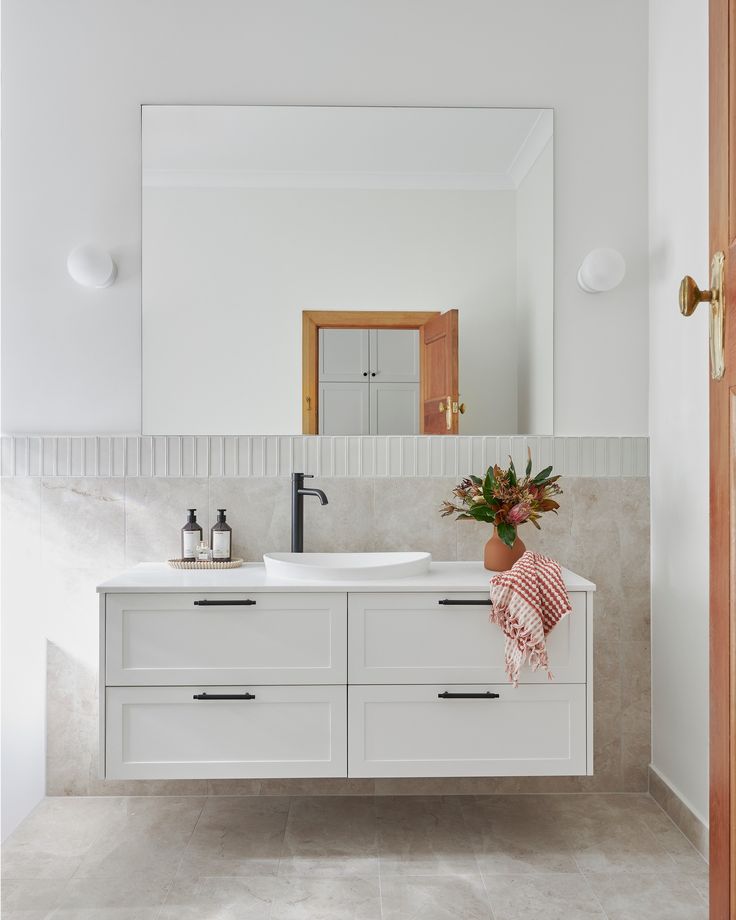 a bathroom with a sink, mirror and potted plant on the counter in front of it