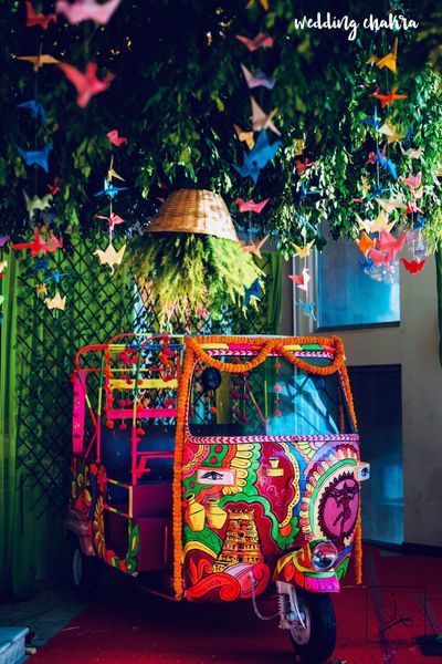 a colorful vehicle parked under a tree filled with paper cranes hanging from it's ceiling