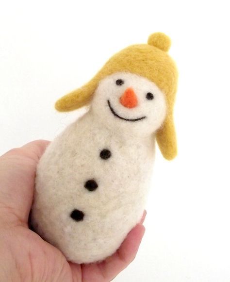 a hand holding a small felt snowman ornament