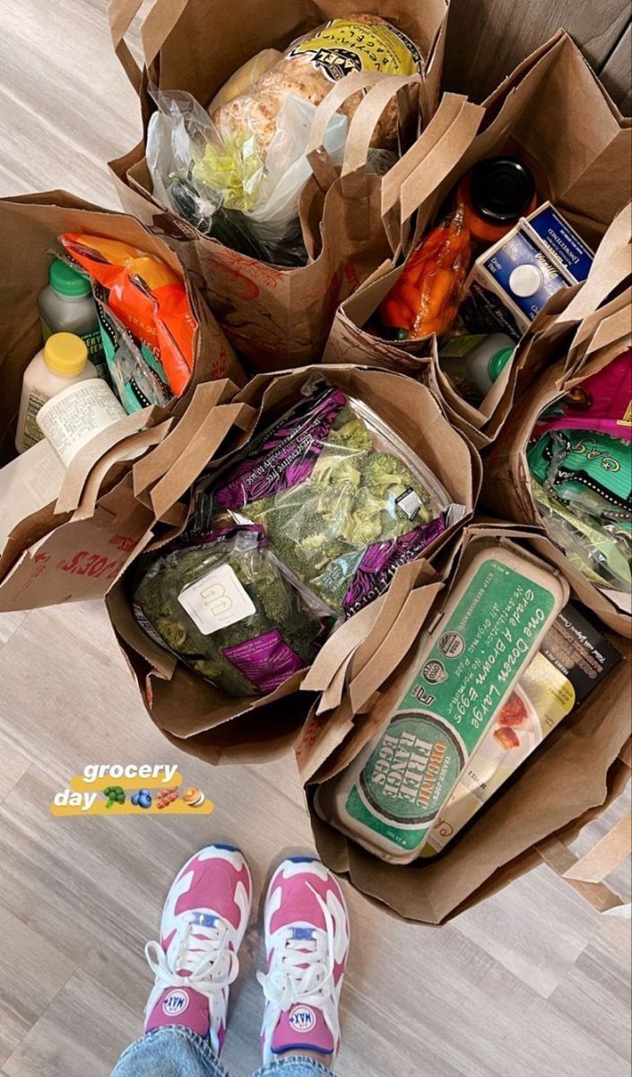 a person standing on the floor with several bags of food in front of their feet