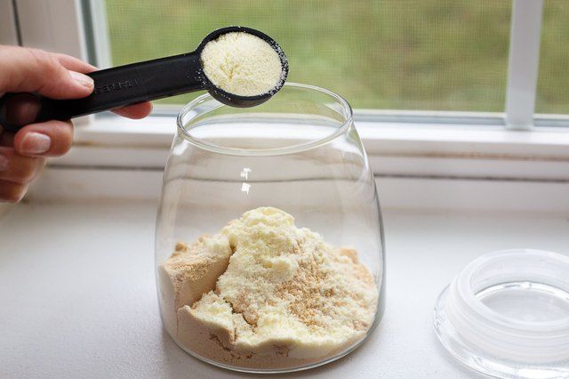 a person scooping sugar into a glass jar