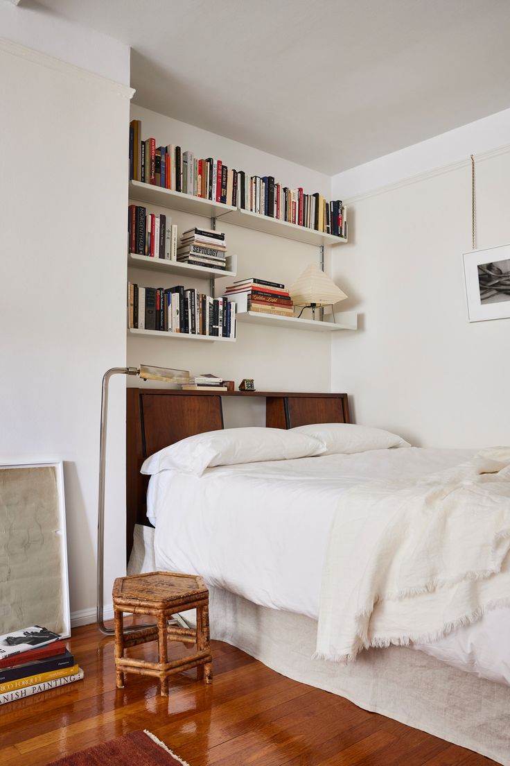 a bedroom with a bed, bookshelf and wooden floors