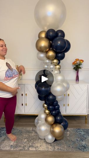 a woman standing in front of a giant balloon arch with metallic balloons on the top