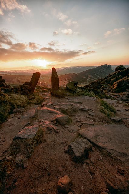 the sun is setting over some rocks in the mountains near an open area with large rock formations