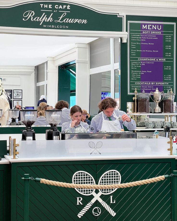 two women are behind the counter at a restaurant with tennis rackets on it and people in the background