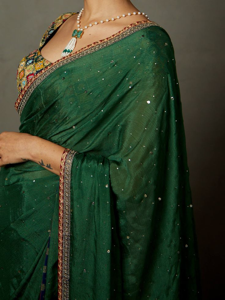 Editor's Note Upgrade your ethnic wardrobe with our elegant green sari with stitched blouse. This ensemble combines timeless style with modern convenience, featuring a beautifully draped sari paired with a matching stitched blouse. The rich green color and exquisite detailing make it a perfect choice for weddings, parties, and special occasions. Make a statement with this graceful and sophisticated outfit Color: Green Fabric: Sari: viscose chinon, blouse: viscose crepe Components: Sari and blous Green Cotton Silk Lehenga For Eid, Pista Green Pre-draped Saree With Mirror Work For Navratri, Green Georgette Choli With Cutdana, Designer Green Dupatta For Transitional Season, Green Cotton Silk Sharara For Festive Occasions, Festive Green Cotton Silk Sharara, Semi-stitched Cotton Silk Pre-draped Saree With Mirror Work, Green Blouse Piece With Resham Embroidery For Transitional Seasons, Designer Pista Green Pre-draped Cotton Silk Saree