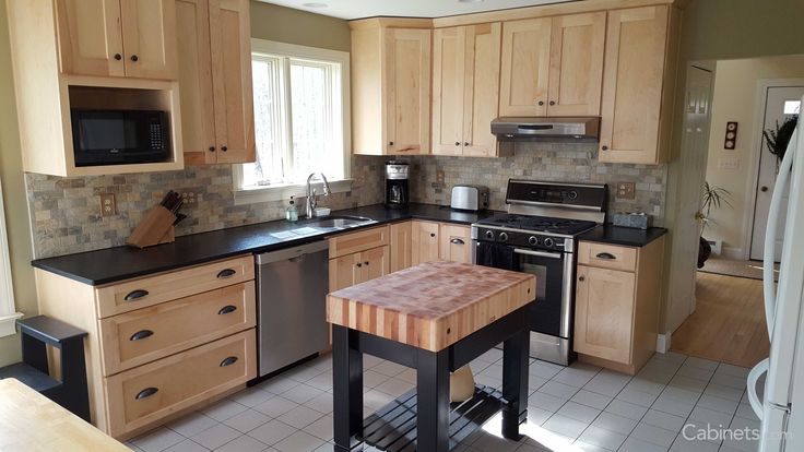 a kitchen with wooden cabinets and black counter tops is shown in this image, there is a butcher block on the island