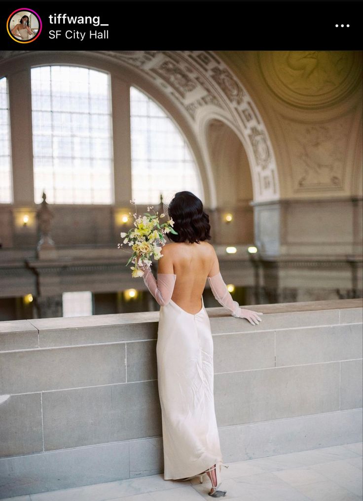 a woman in a long white dress holding flowers