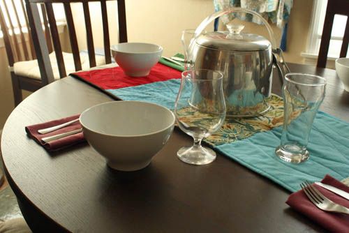 a dining room table with place settings and dishes on it, including a teapot