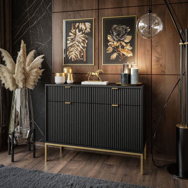 a black and gold sideboard with two pictures on the wall next to it in a living room