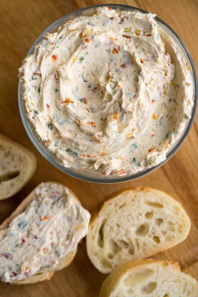 a glass bowl filled with cream cheese and sprinkles next to slices of bread