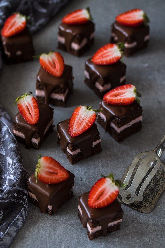 there are many pieces of cake and strawberries on the table next to a fork