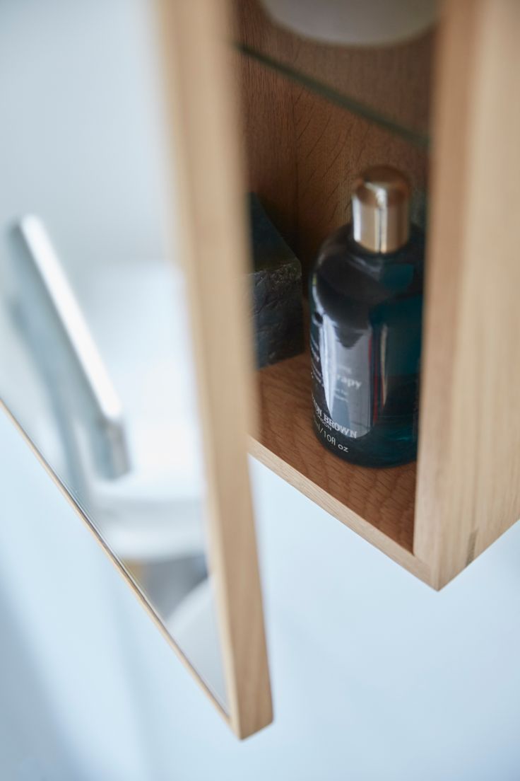 a bottle of cologne sitting on top of a wooden shelf next to a toilet paper dispenser