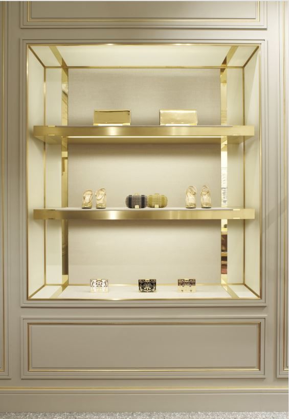 an empty display case with gold trim and shelves filled with bottles, candles, and other items