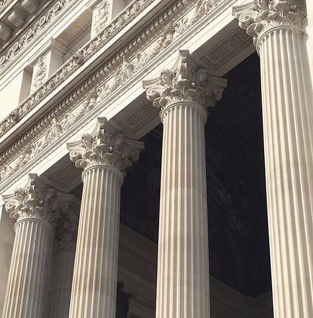 an old building with columns and clocks on the front