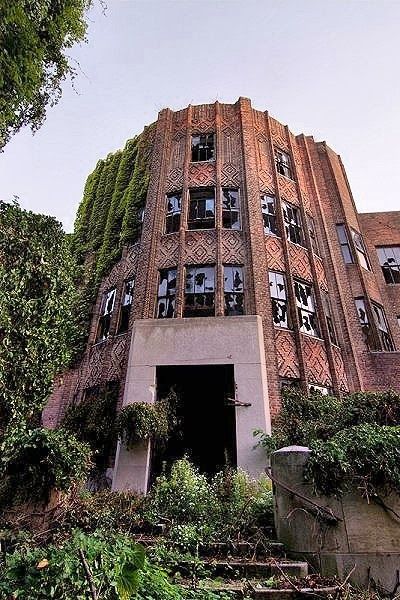 an old brick building with ivy growing on it's side and stairs leading up to the entrance