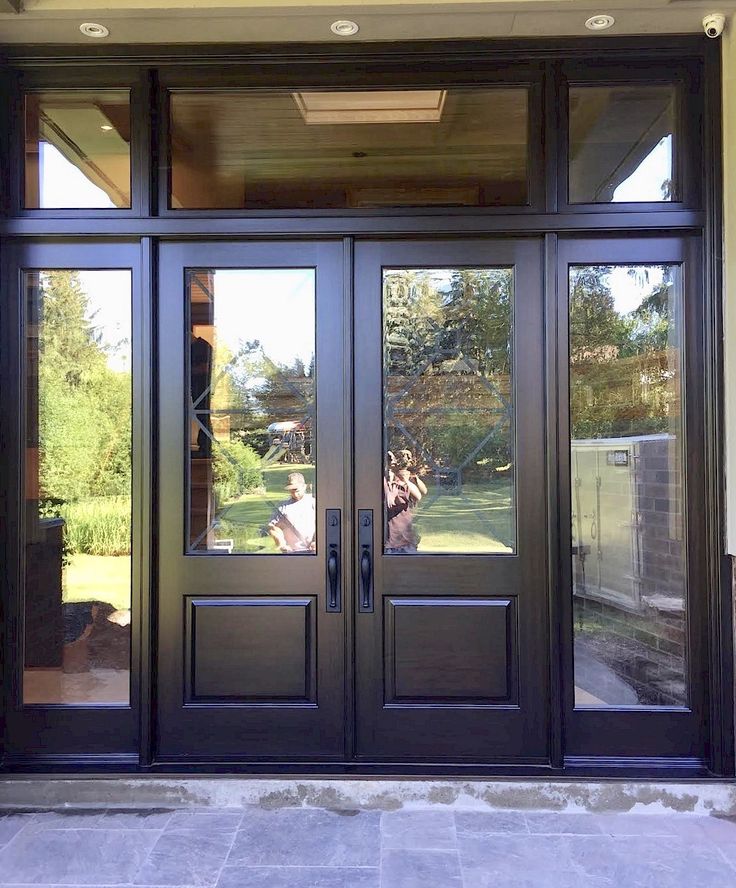 the front entrance to a home with double doors and glass panels on both sides,